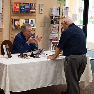 John 麦克维恩 talks to someone at his book signing